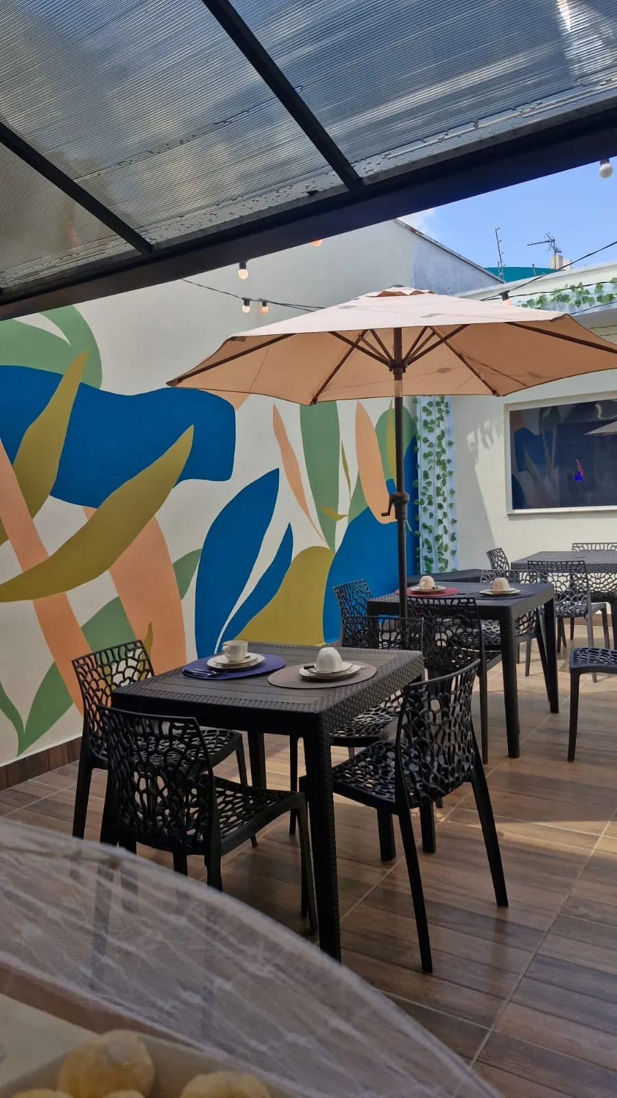 Área de convivência com mesas e mural colorido